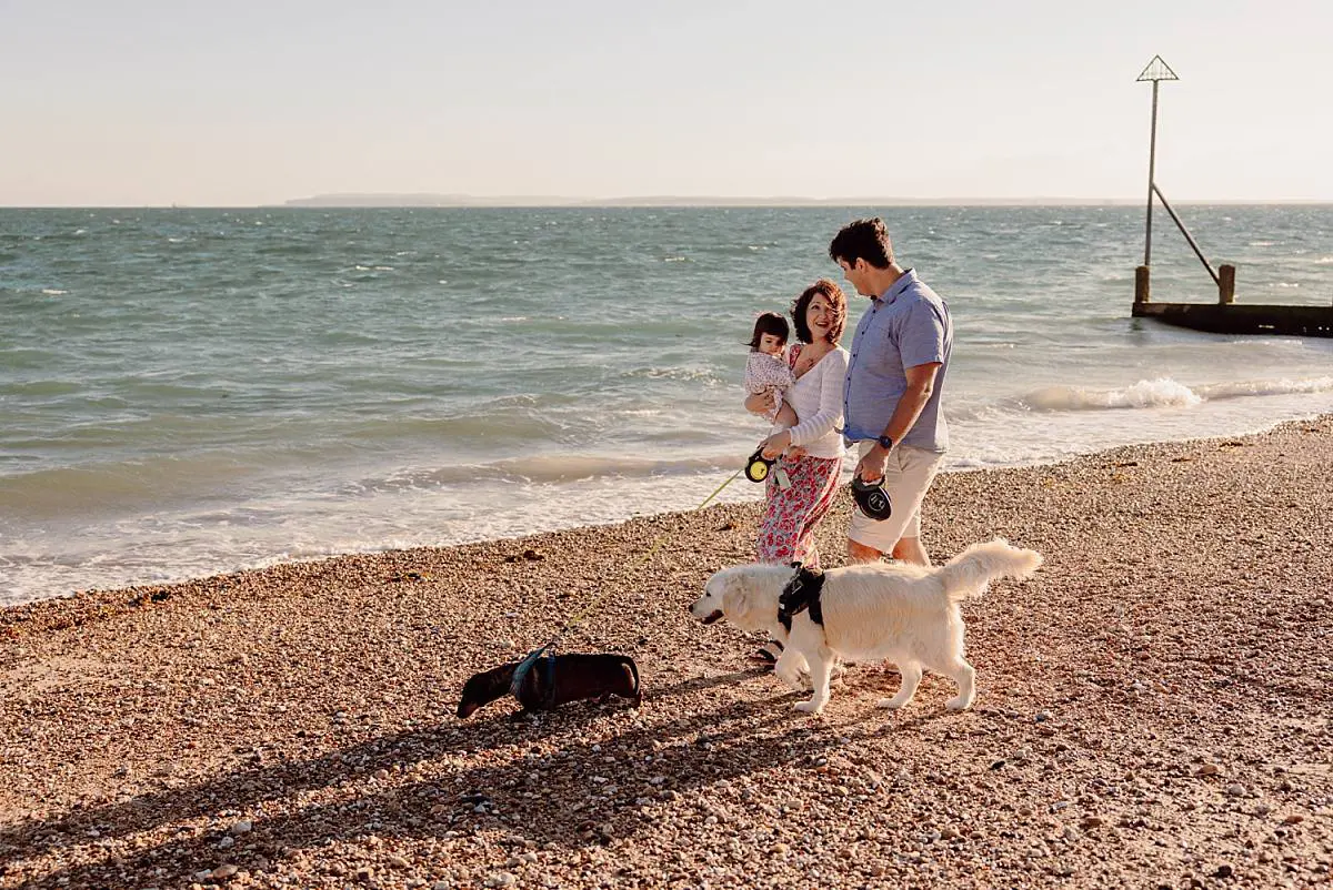 Family enjoying a sunset beach photo shoot on Hayling Island with their two dogs and one-year-old daughter