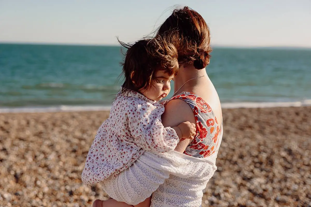 Family enjoying a sunset beach photo shoot on Hayling Island with their two dogs and one-year-old daughter
