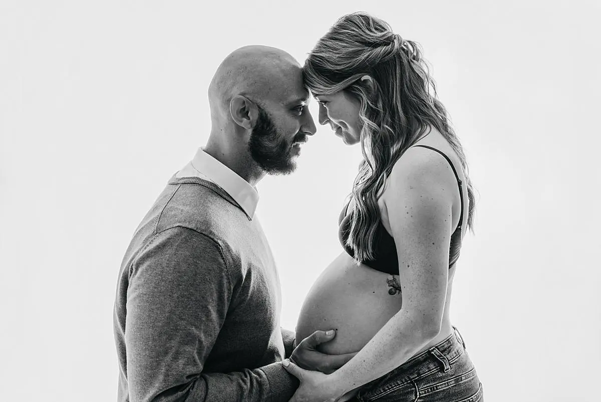 black and white classic photograph of couple being close and holding belly, emotive image by Fareham photographer Ania Photo