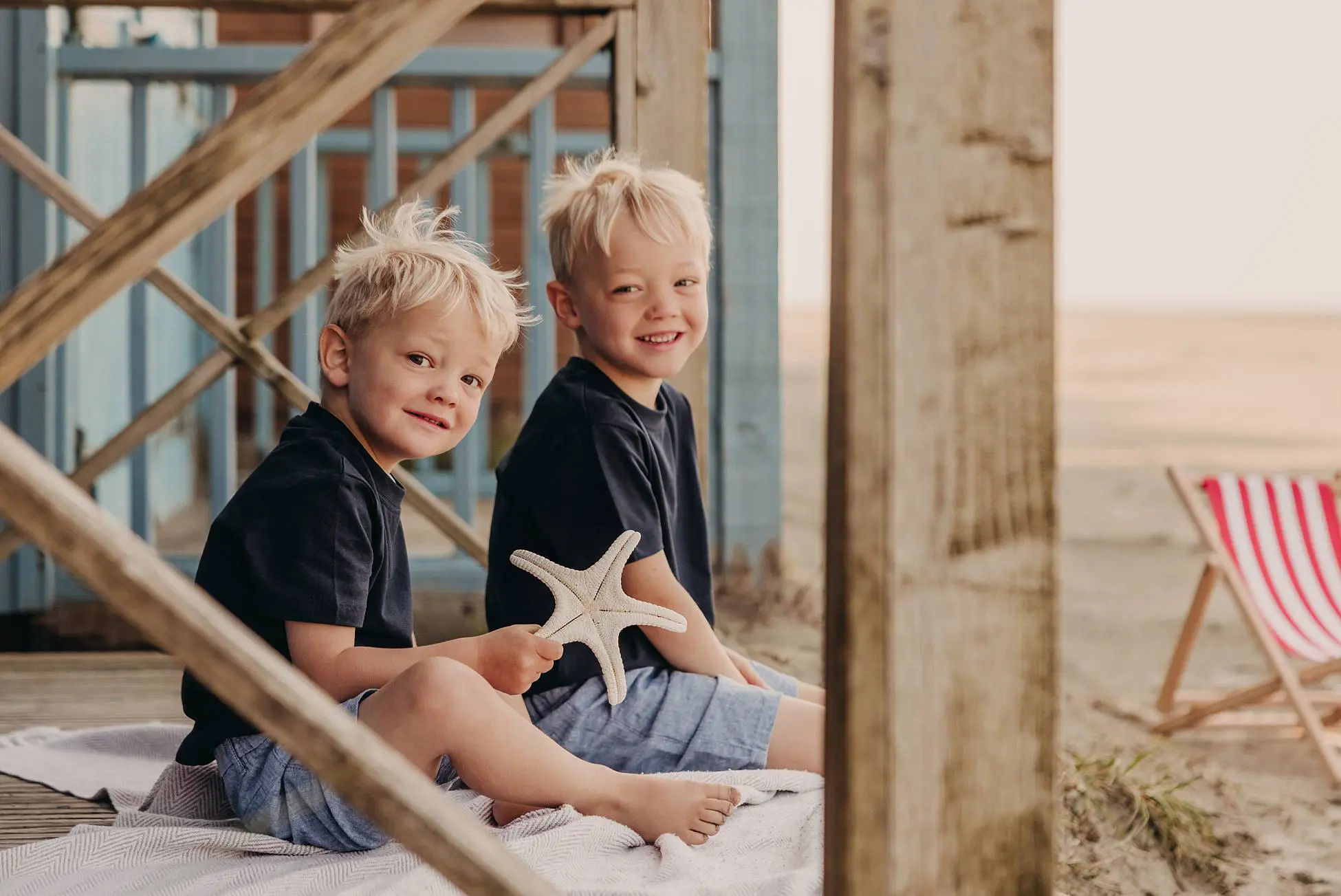 Brothers sitting on beach steps, smiling and playing together with natural light