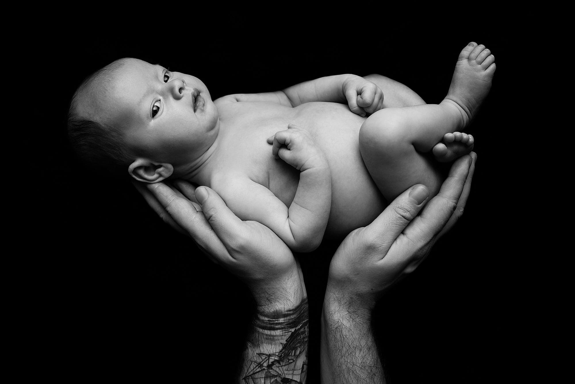 timeless photograph of newborn baby in dads hands simba pose by Ania Photo professional Portsmouth newborn photographer