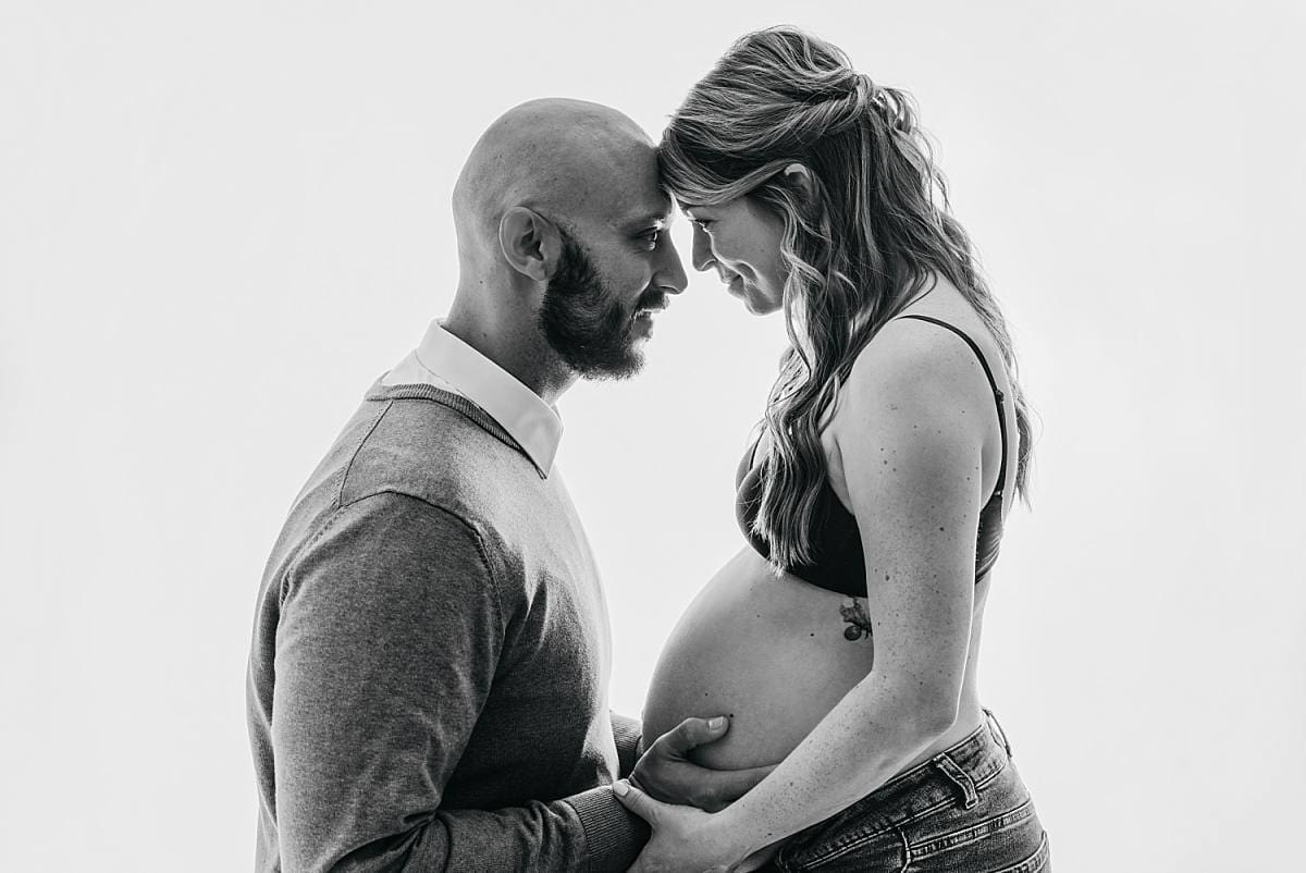 black and white classic photograph of couple being close and holding belly, emotive image by Fareham photographer Ania Photo