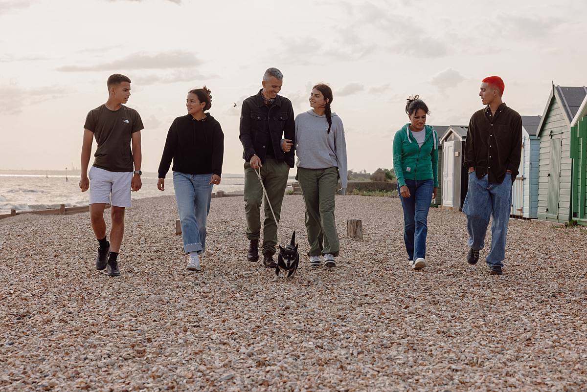Family group photo at Lee-On-Solent Beach with teenage kids, framed by soft waves and a beautiful, sunlit sky