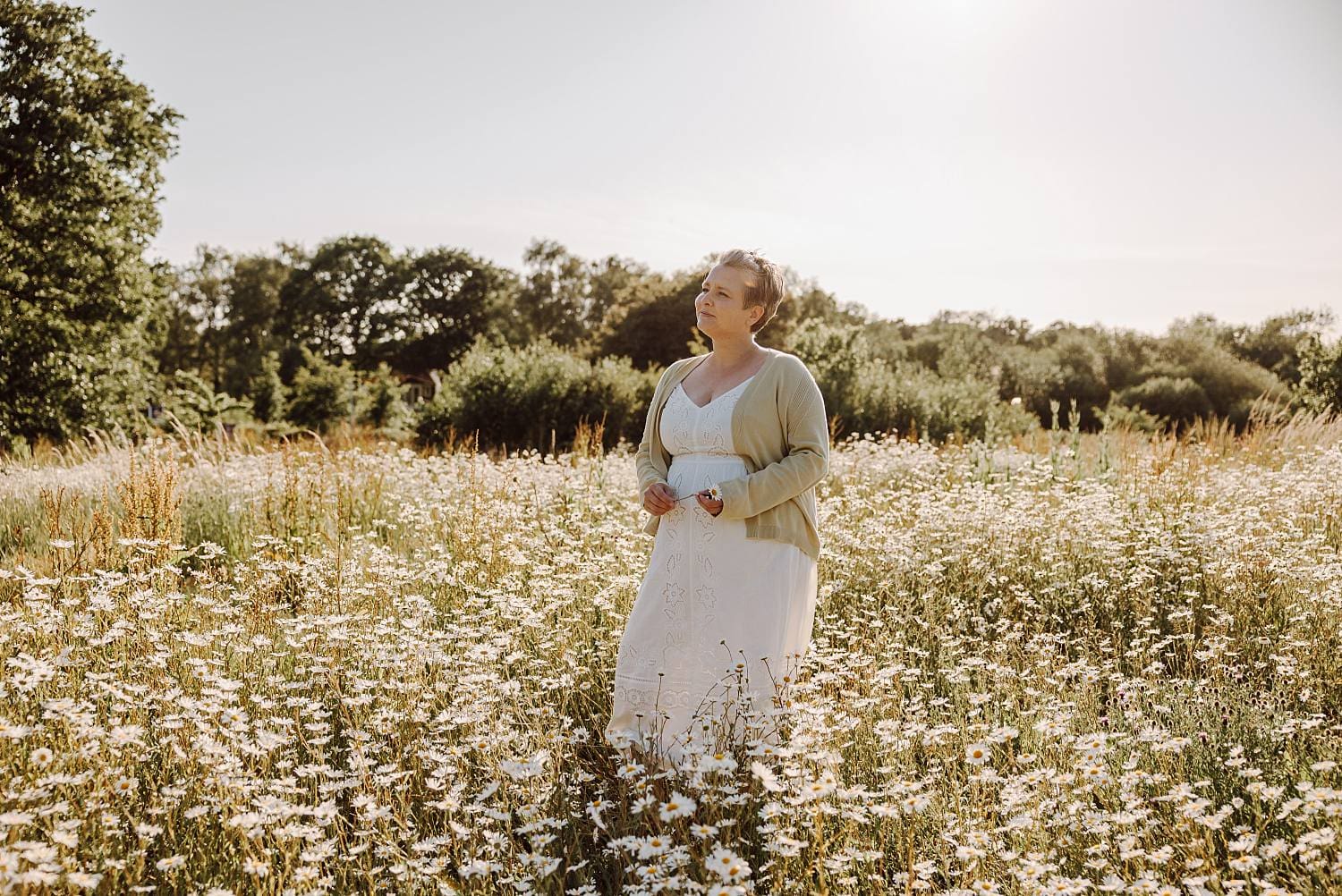 Natural family portrait in daisy field with soft summer light