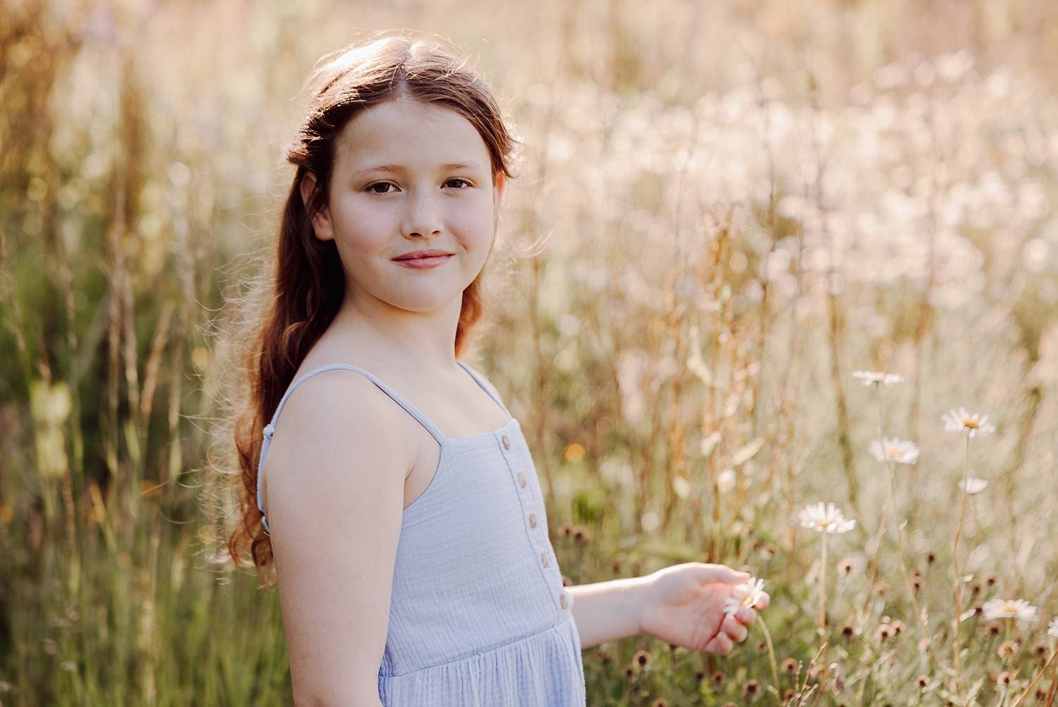 Natural family portrait in daisy field with soft summer light