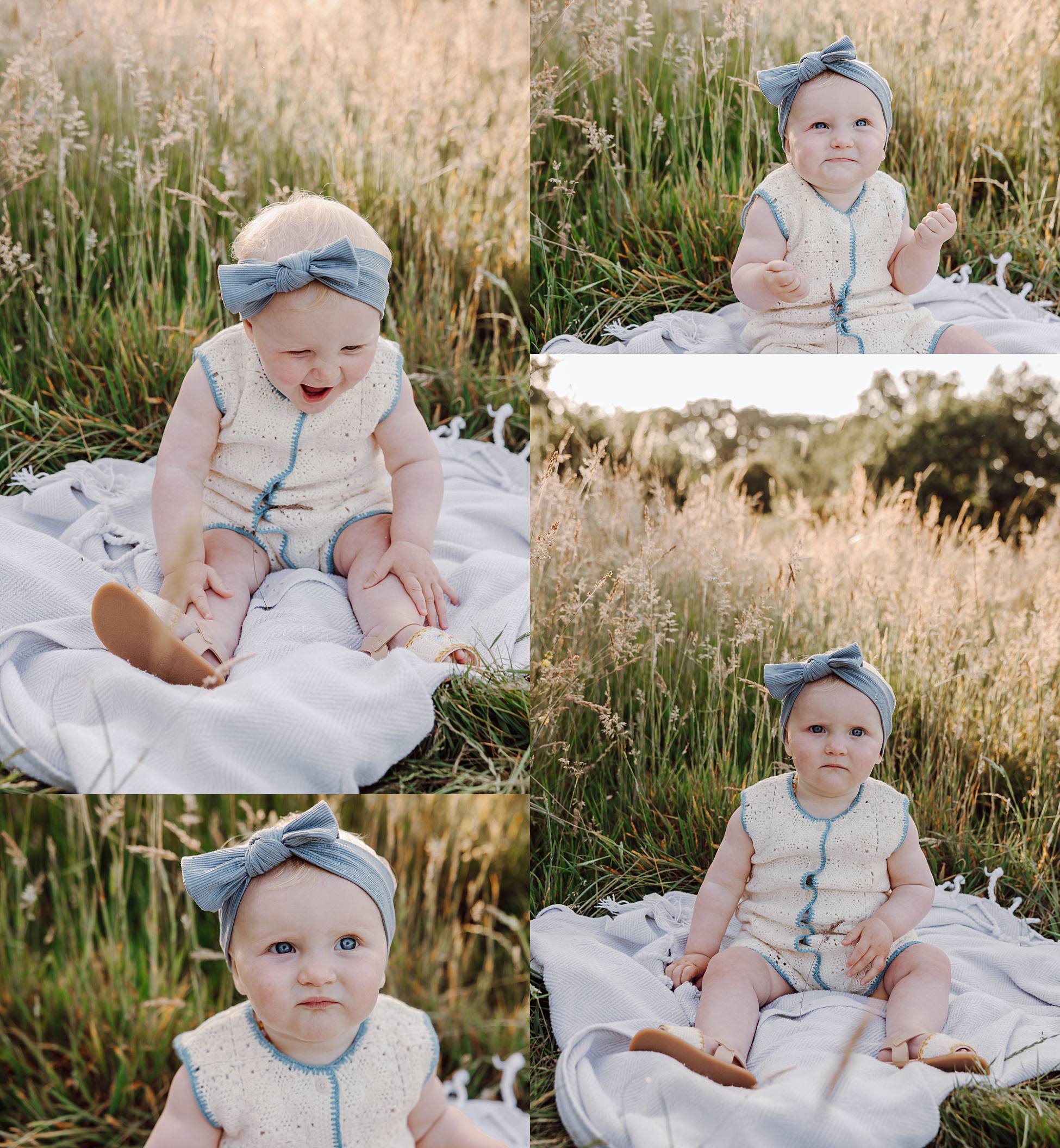 Baby girl with bow headband sitting on blanket in meadow