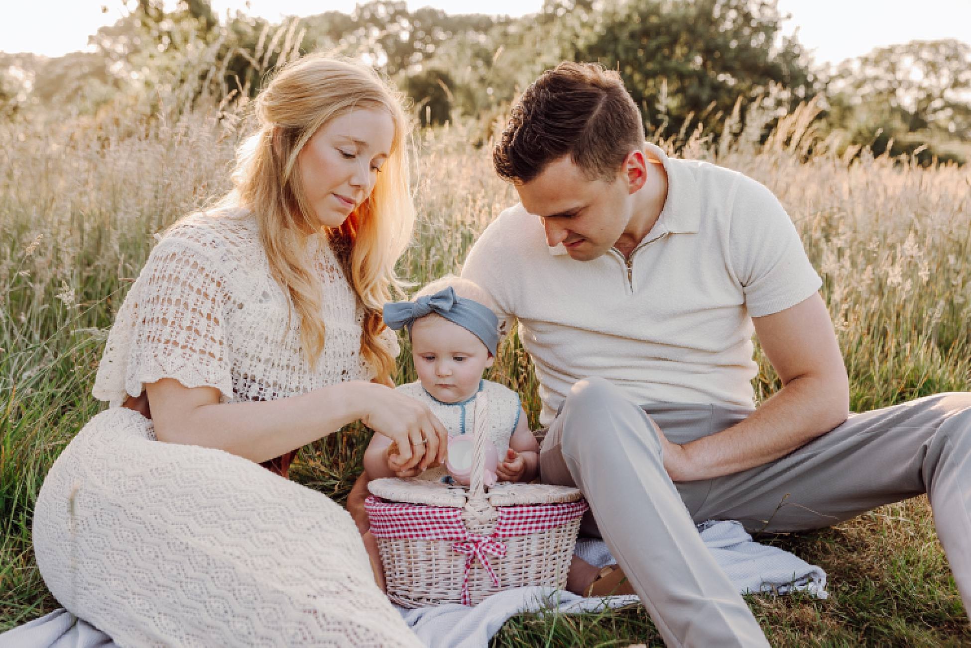 Family relaxing together on picnic blanket at golden hour