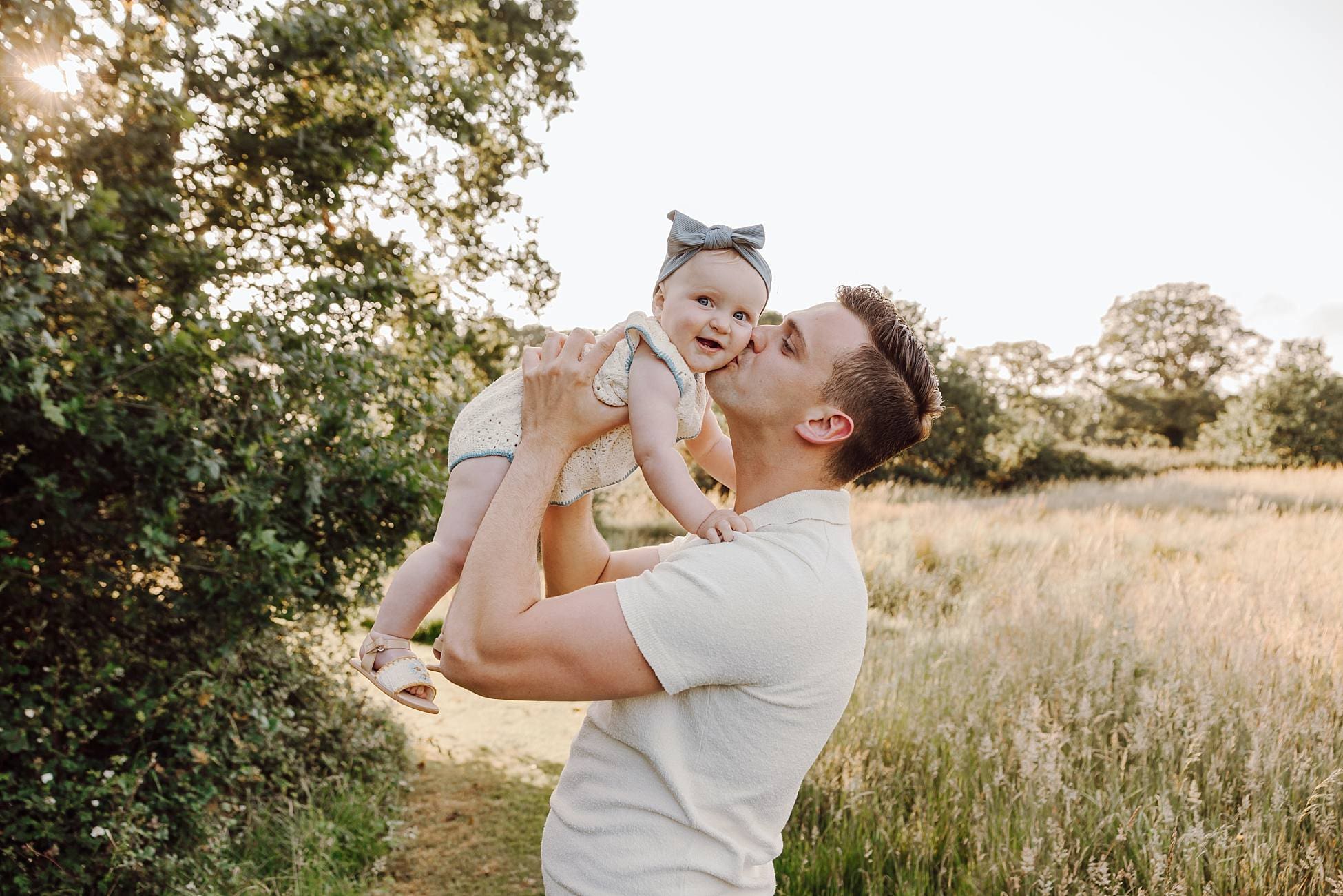 Dad lifting toddler into the air at sunset in Waterlooville