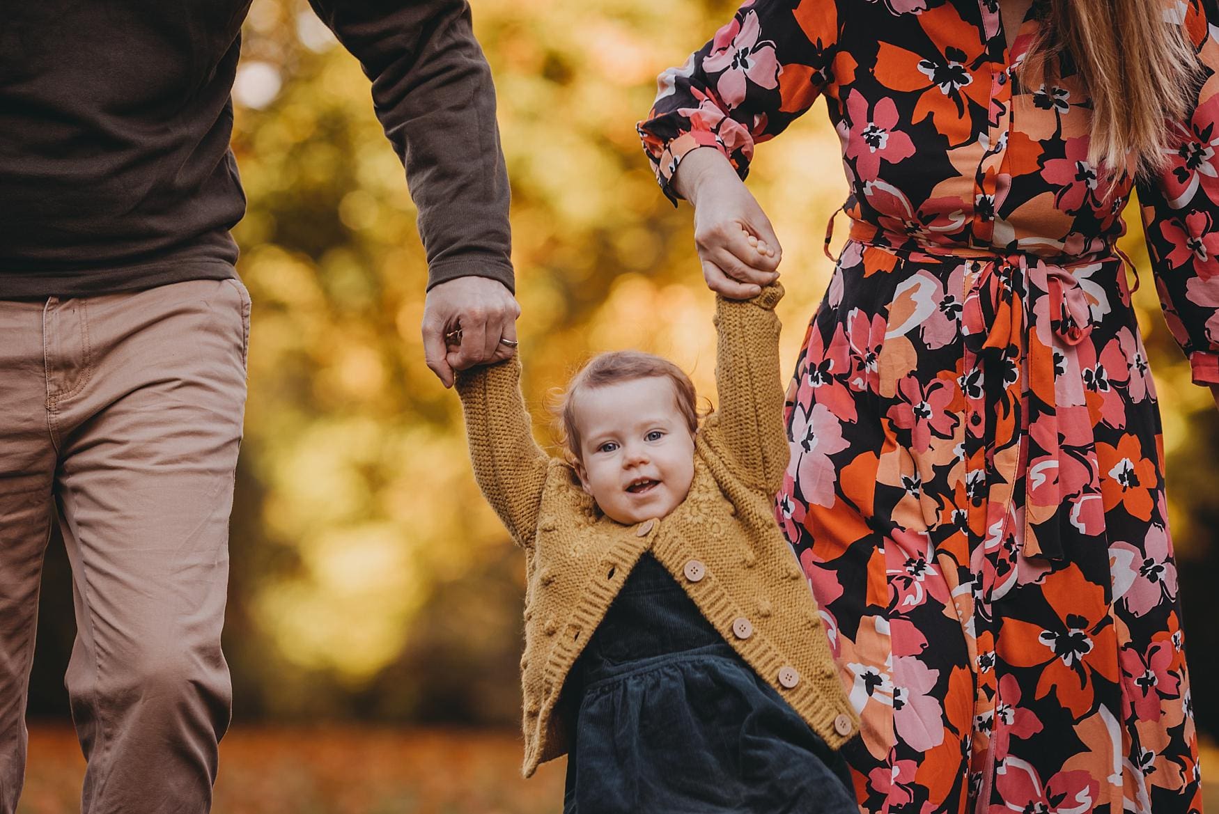 Family walking hand in hand during autumn photoshoot at Queen Elizabeth Country Park, Hampshire.