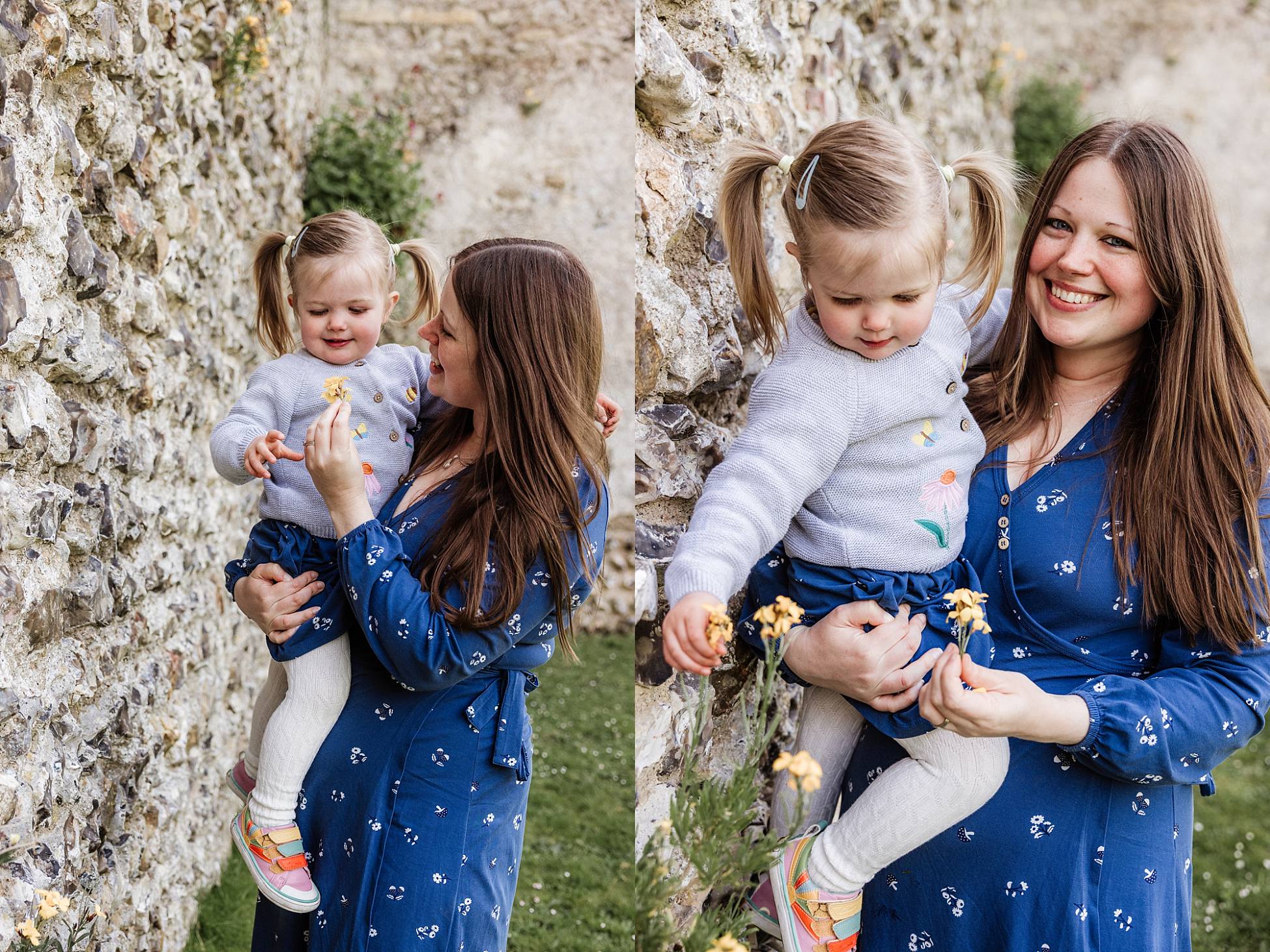 Mum holding toddler, exploring flowers by the castle wall