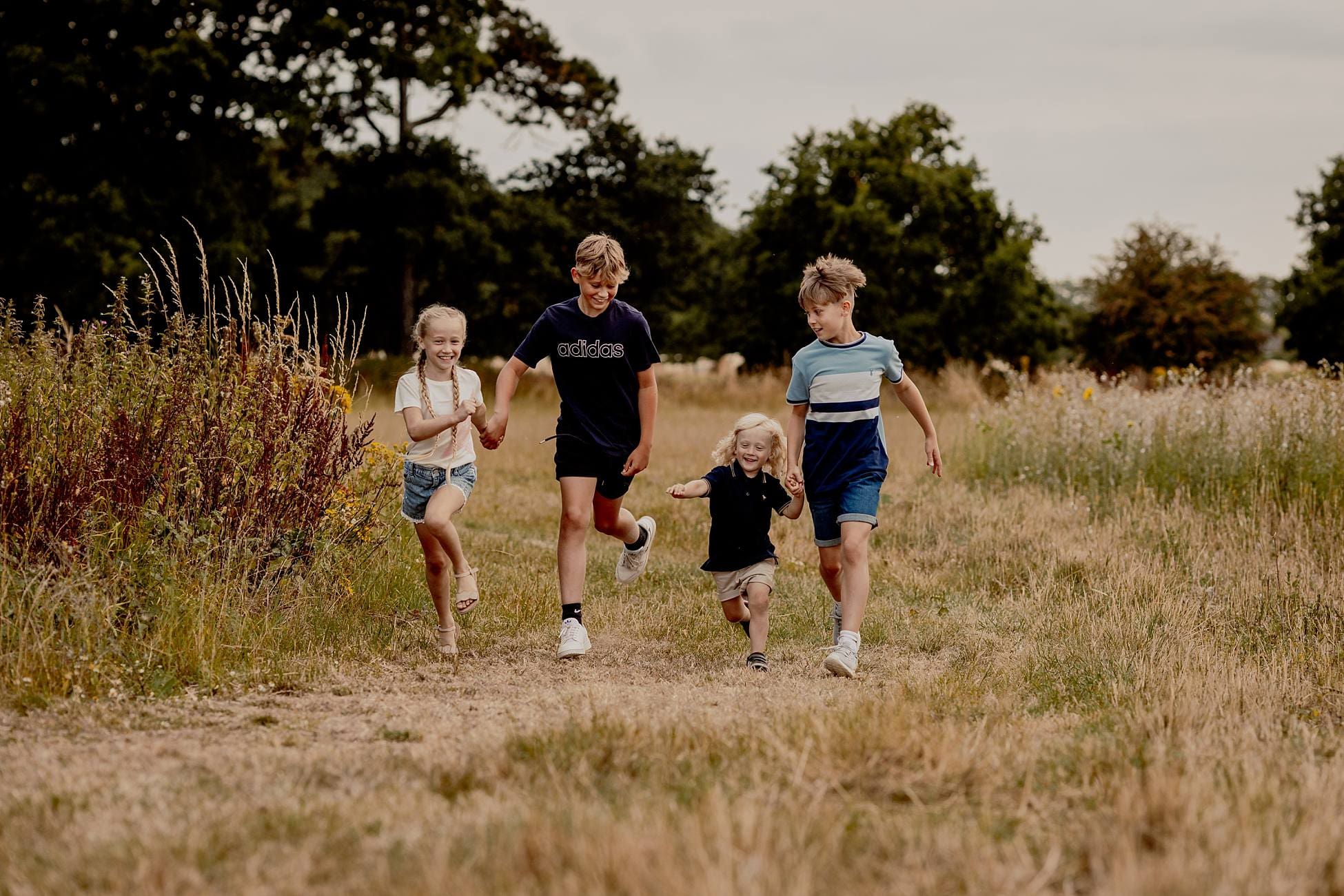 children playing and laughing together during candid family photography in Hampshire sunflower field