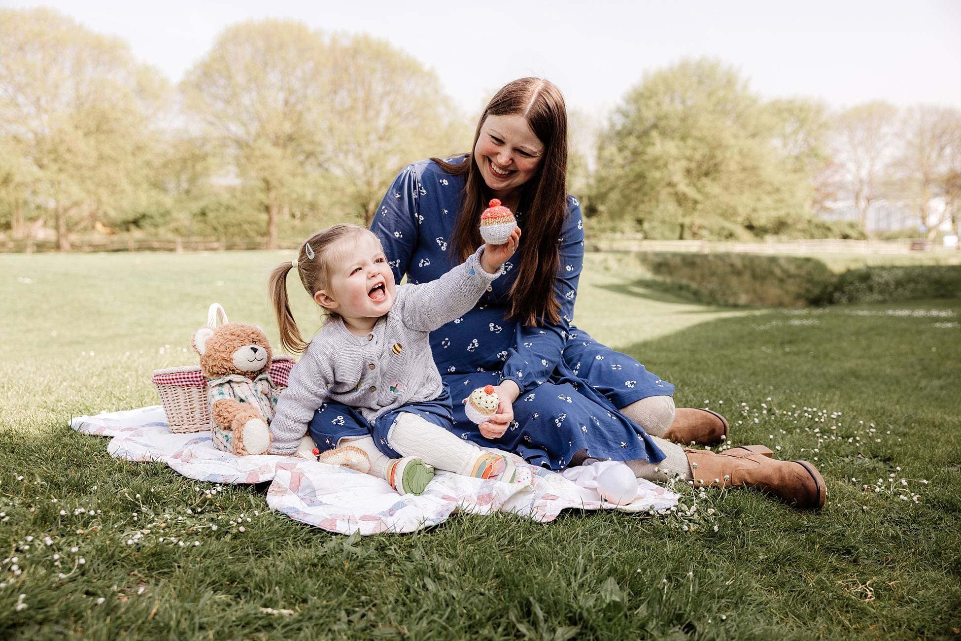 Mum and toddler sharing a laugh on picnic blanket outdoors
