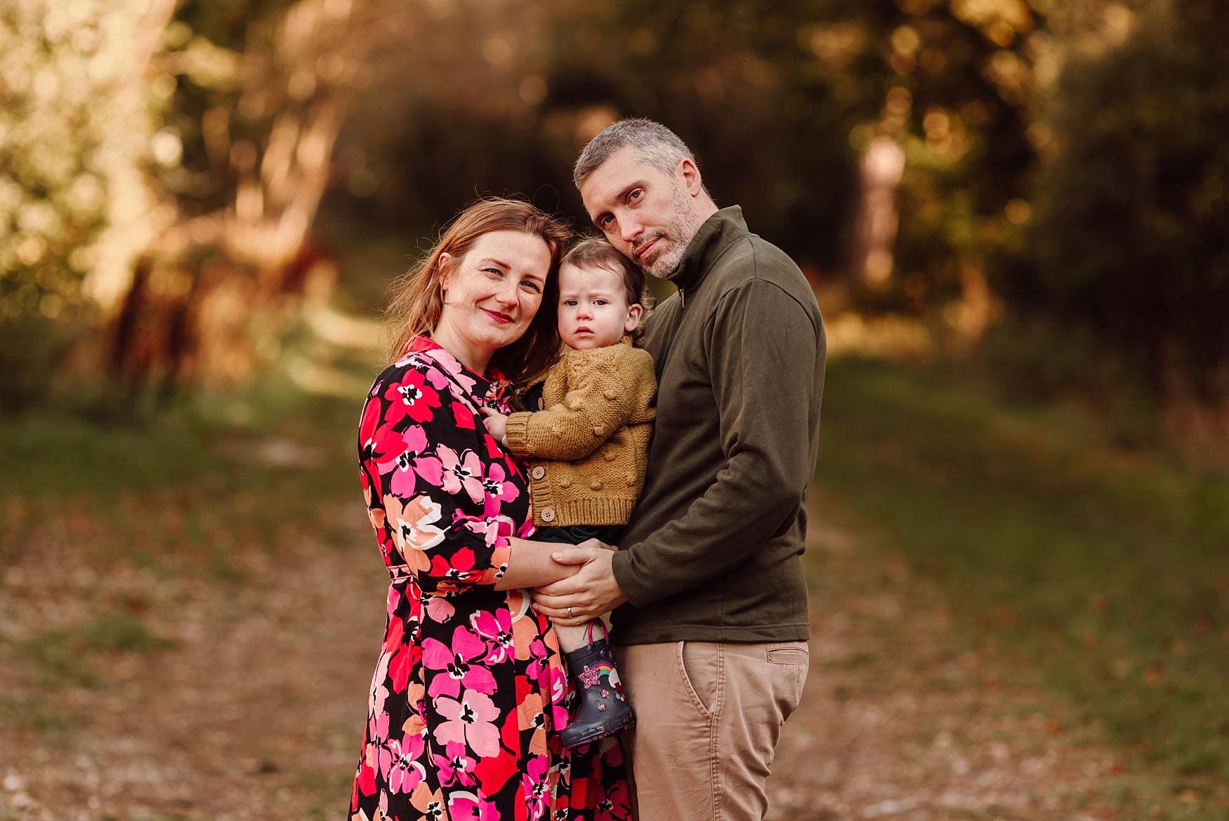 Autumn family photography session in Hampshire with parents holding their child in the park