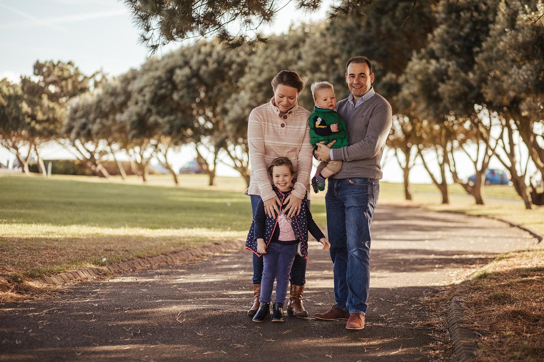 Family standing together on a tree-lined path in Southsea, Portsmouth, during a relaxed outdoor photoshoot
