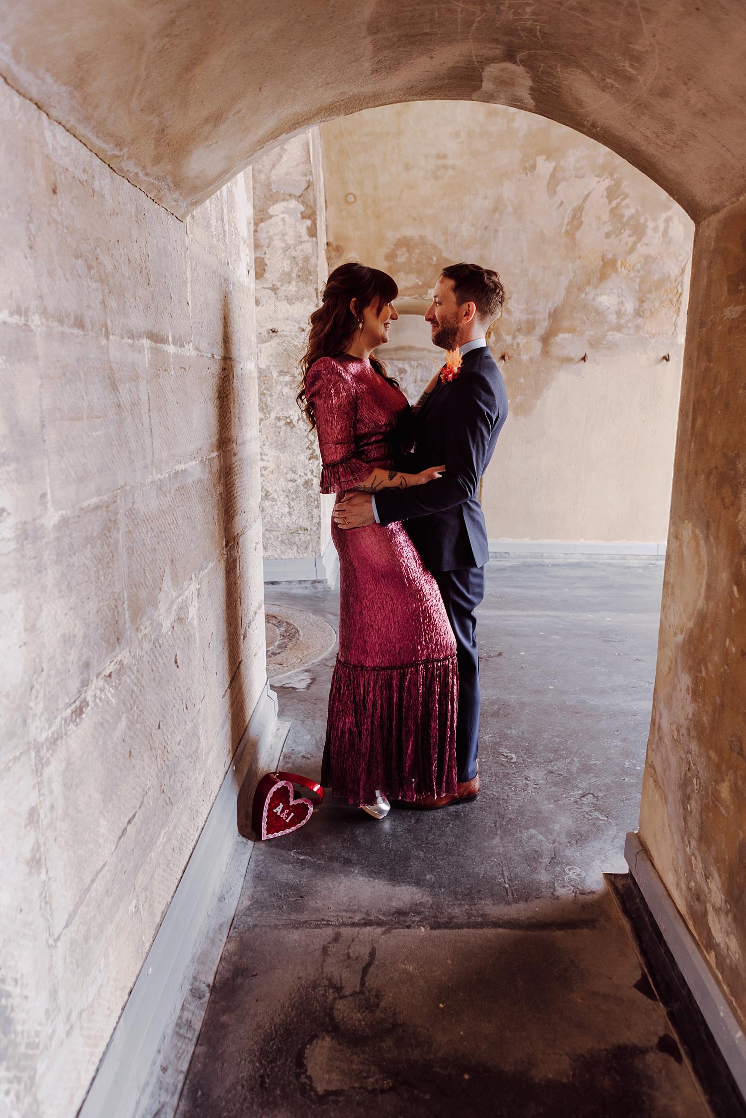 Couple embracing inside historic stone arch at Hotwalls Old Portsmouth during seaside wedding portraits