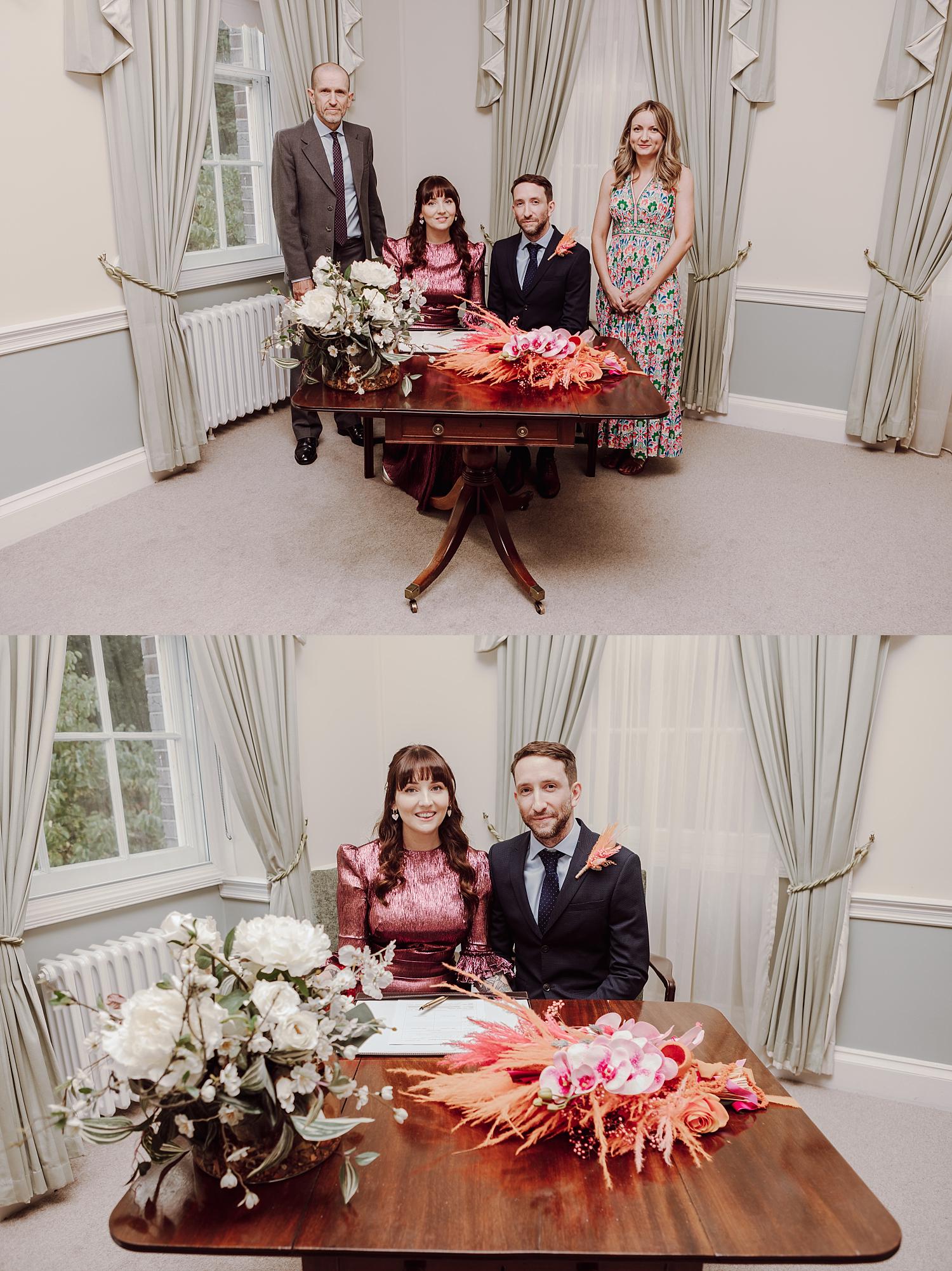 Bride and groom signing the register at Portsmouth Register Office surrounded by close family