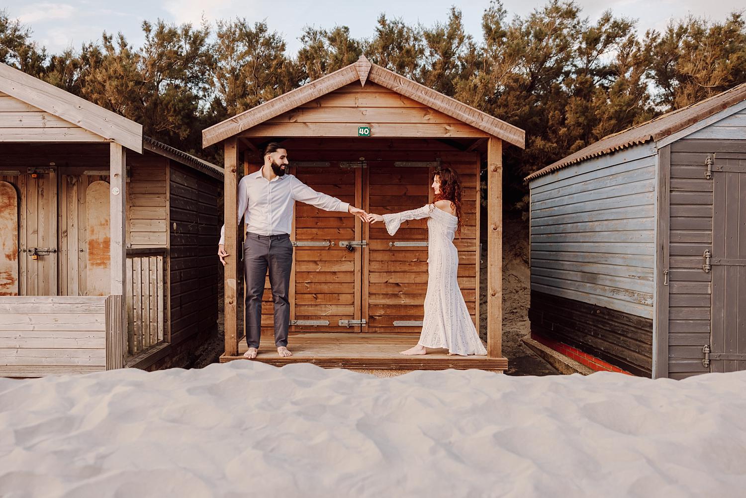 Romantic golden hour engagement portrait of couple standing together on West Wittering Beach in West Sussex.