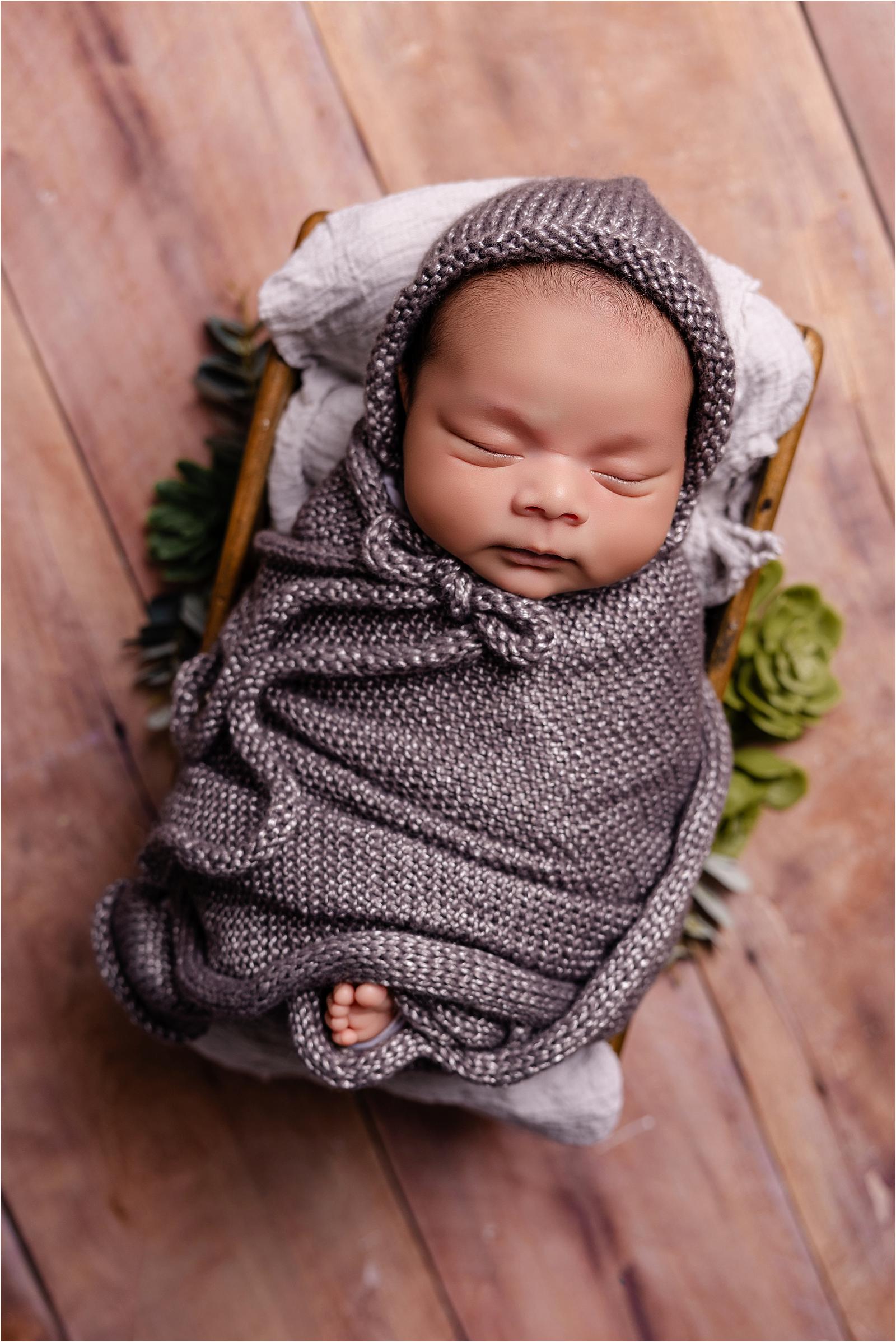 Sleeping newborn baby boy wrapped in grey knit with green floral detail, newborn photographer Littlehampton