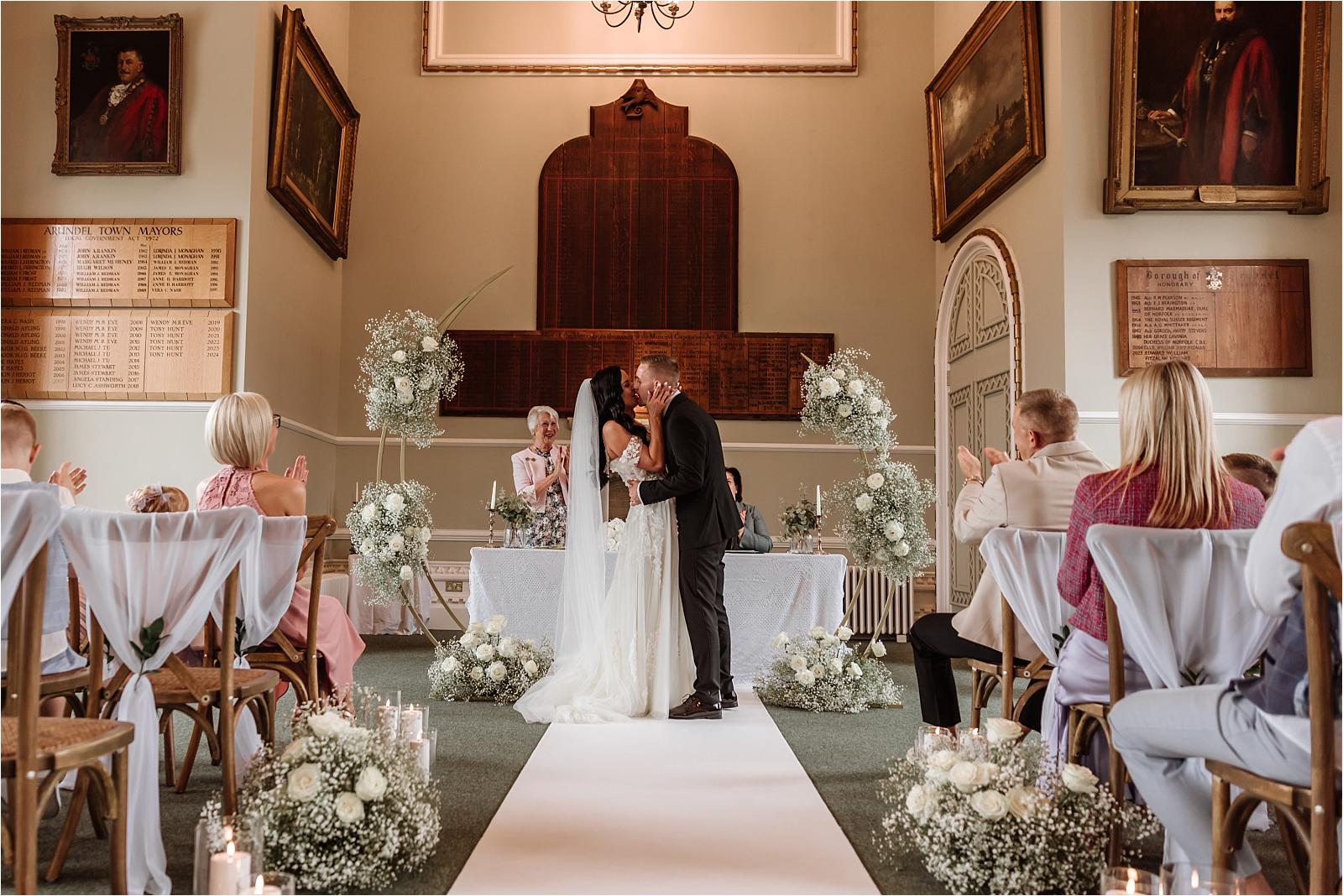Couple standing at the flower-dressed ceremony table in the Atherley Chamber, photographed by an Arundel Town Hall wedding photographer