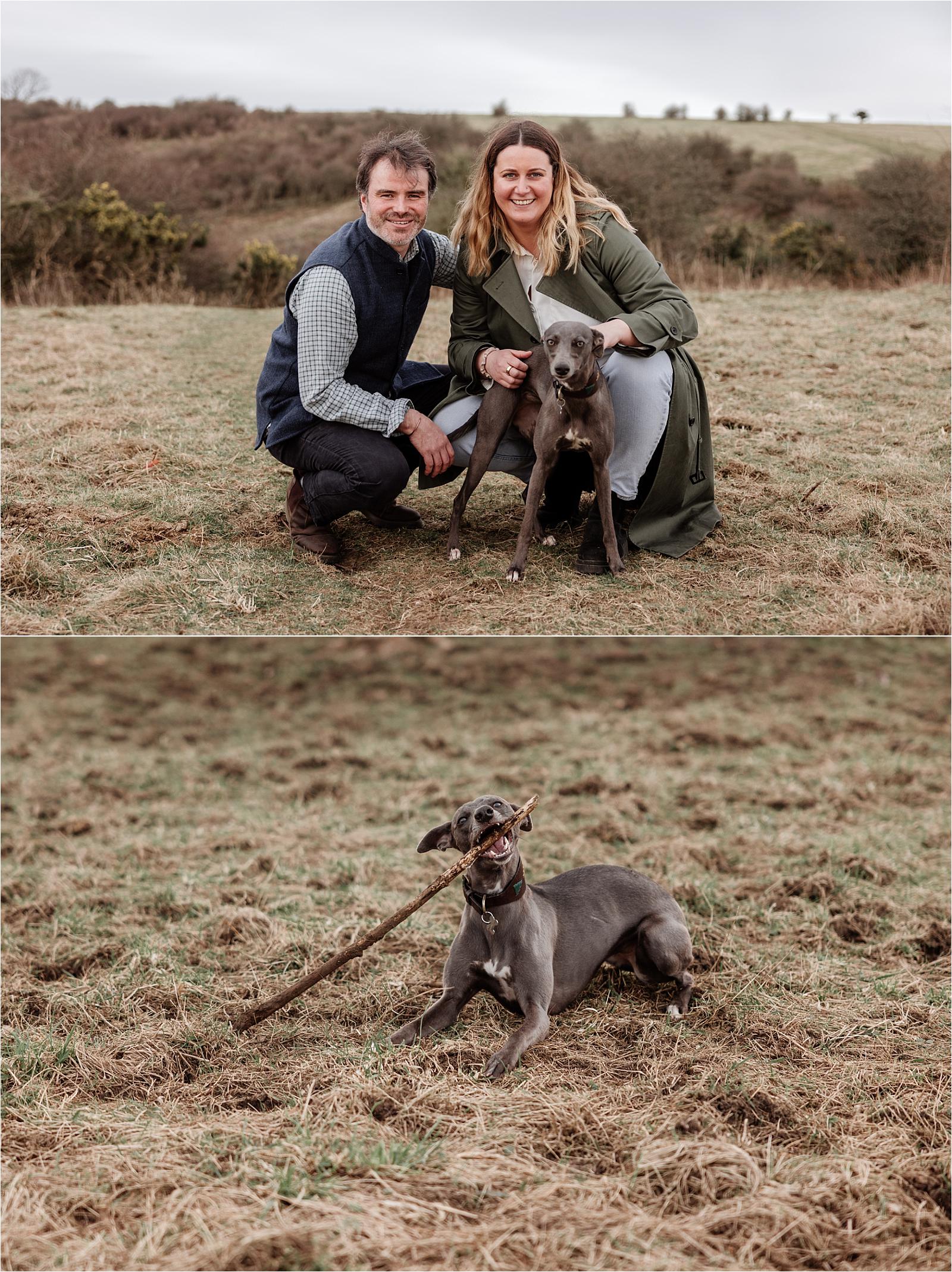 Couple crouching beside their whippet during a dog friendly engagement shoot at Butser Hill
