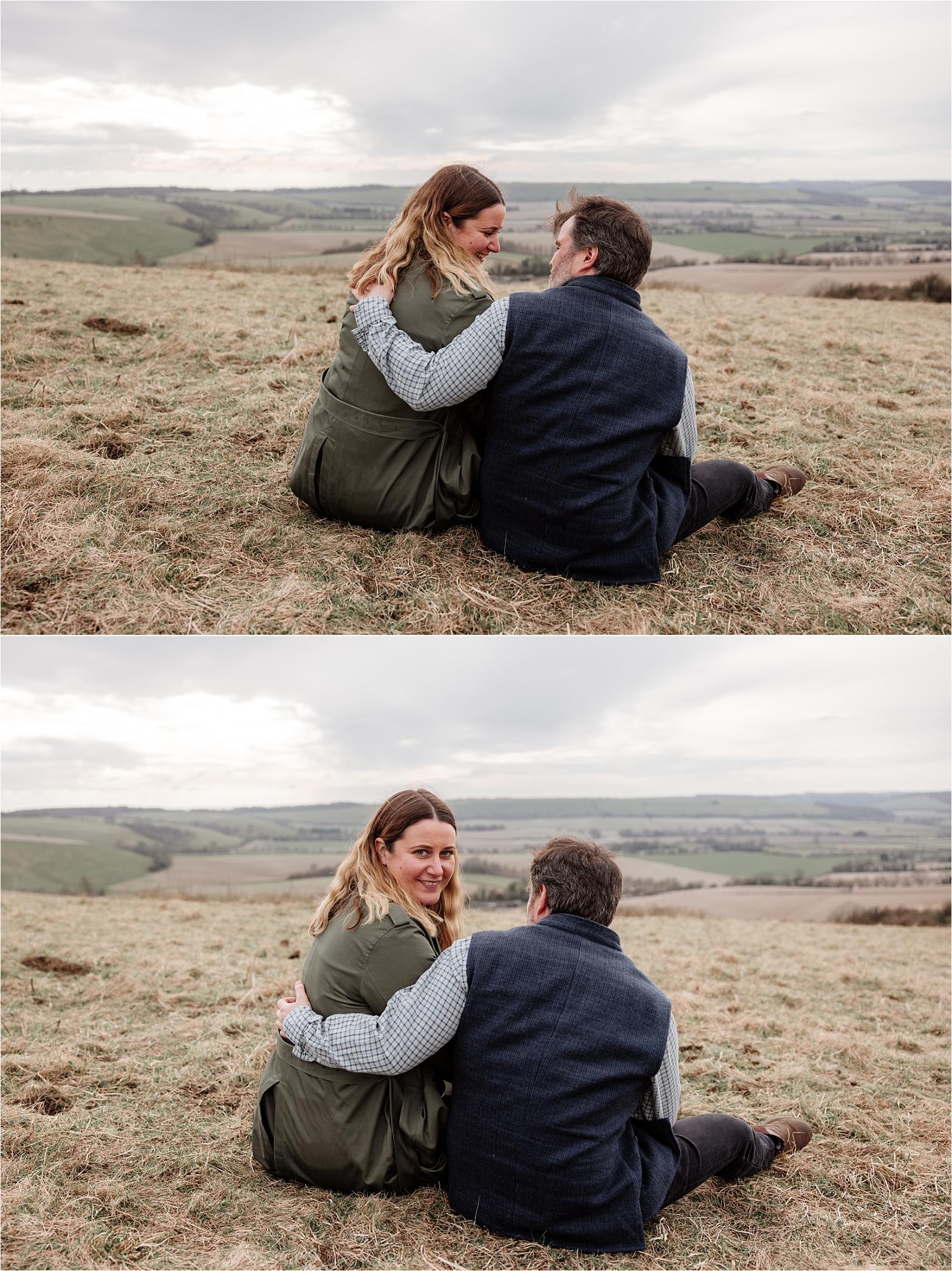 Couple sitting close on the hillside looking out over sweeping South Downs views