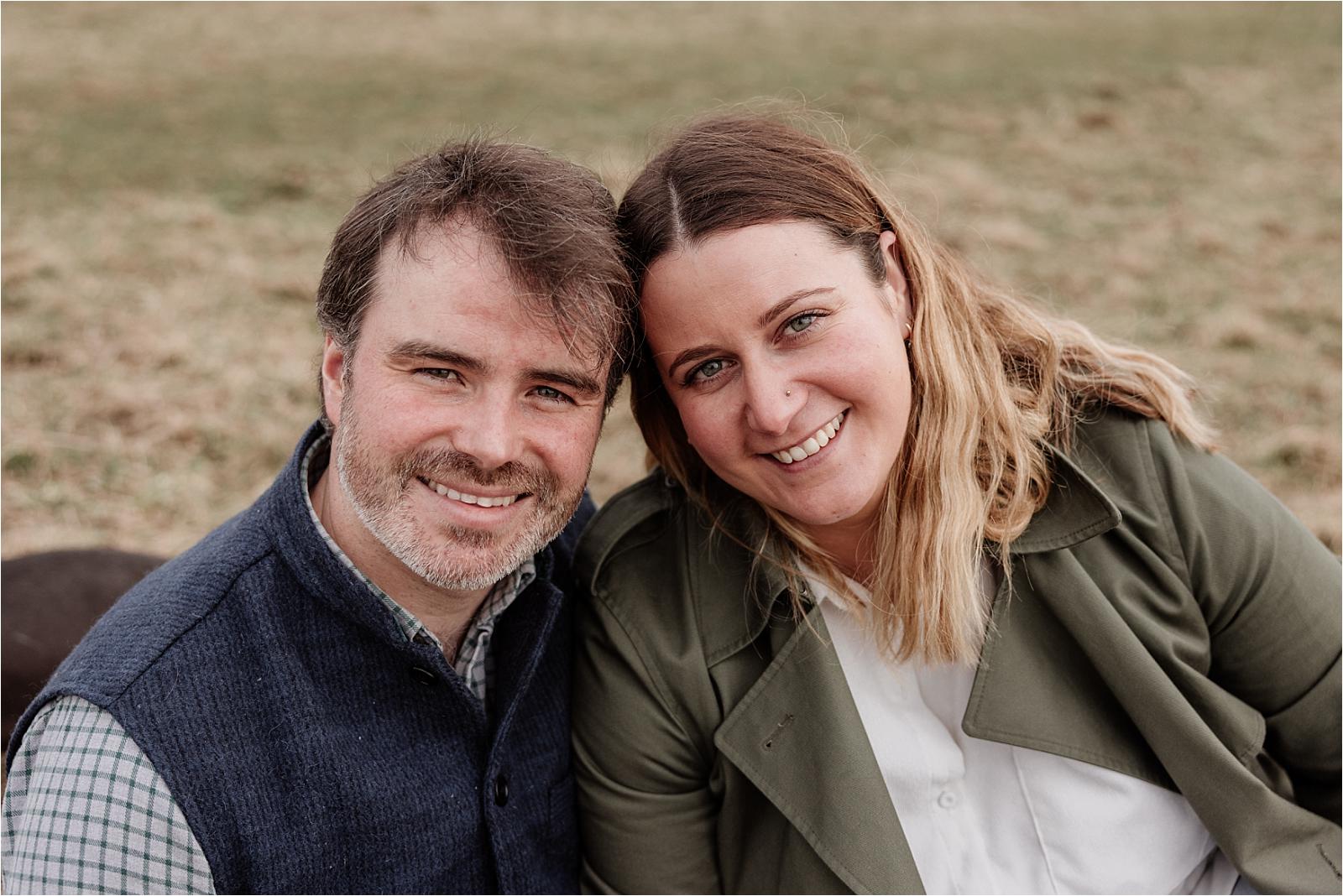 Relaxed close-up portrait of an engaged couple in autumn layers on the South Downs