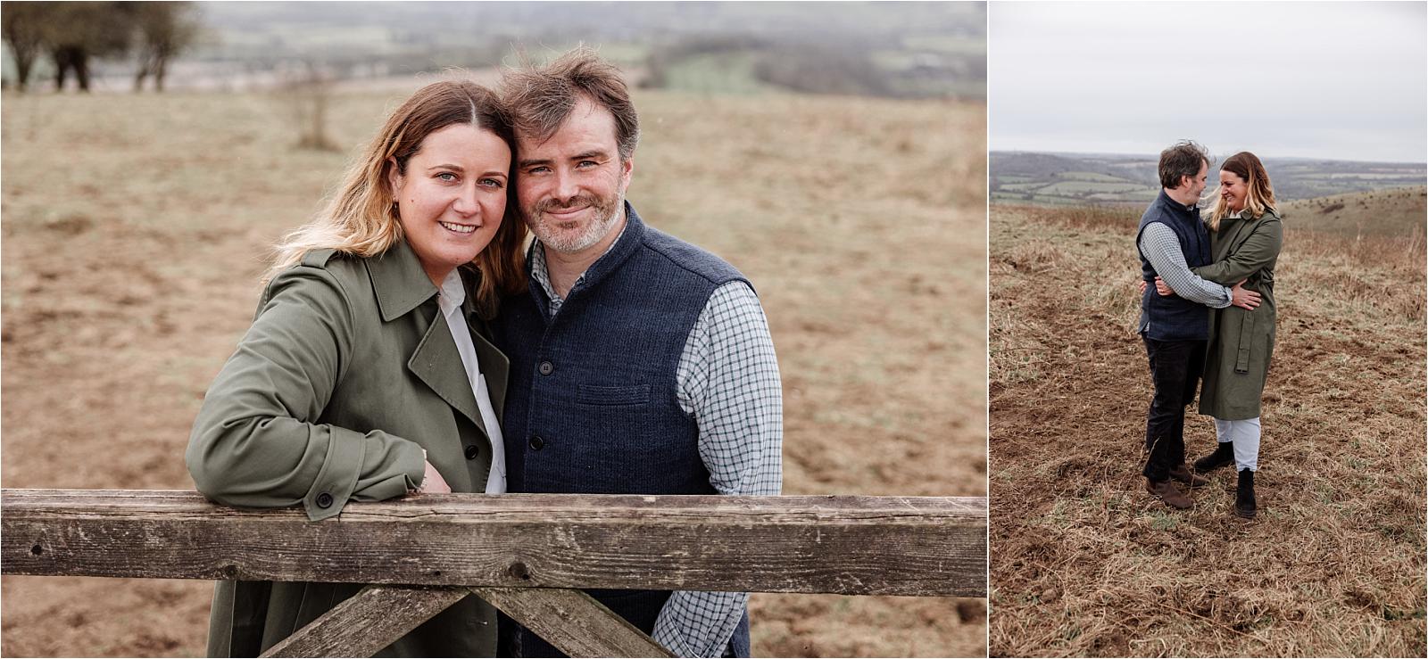 Happy engaged couple smiling together on open grassland at Butser Hill
