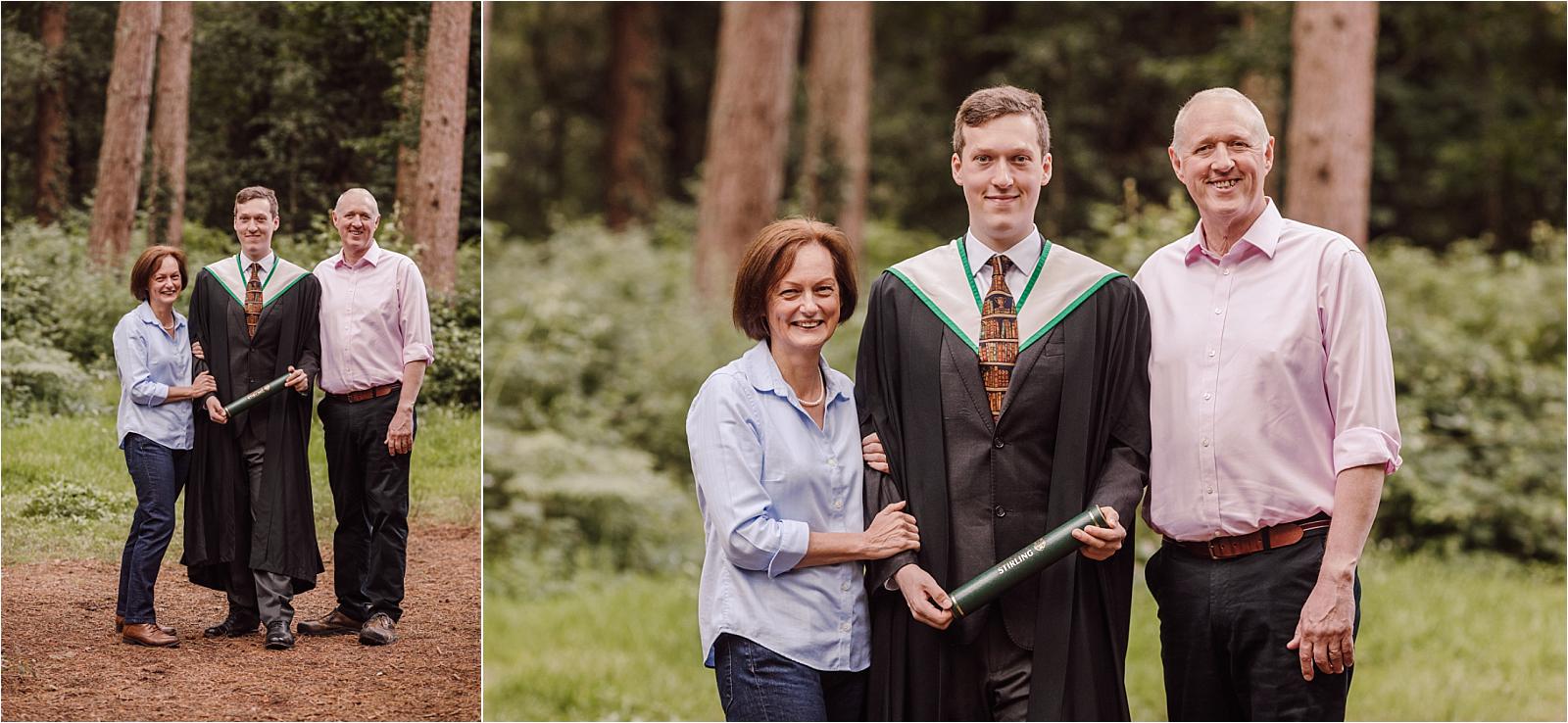 Proud parents standing either side of their graduate son among tall pine trees