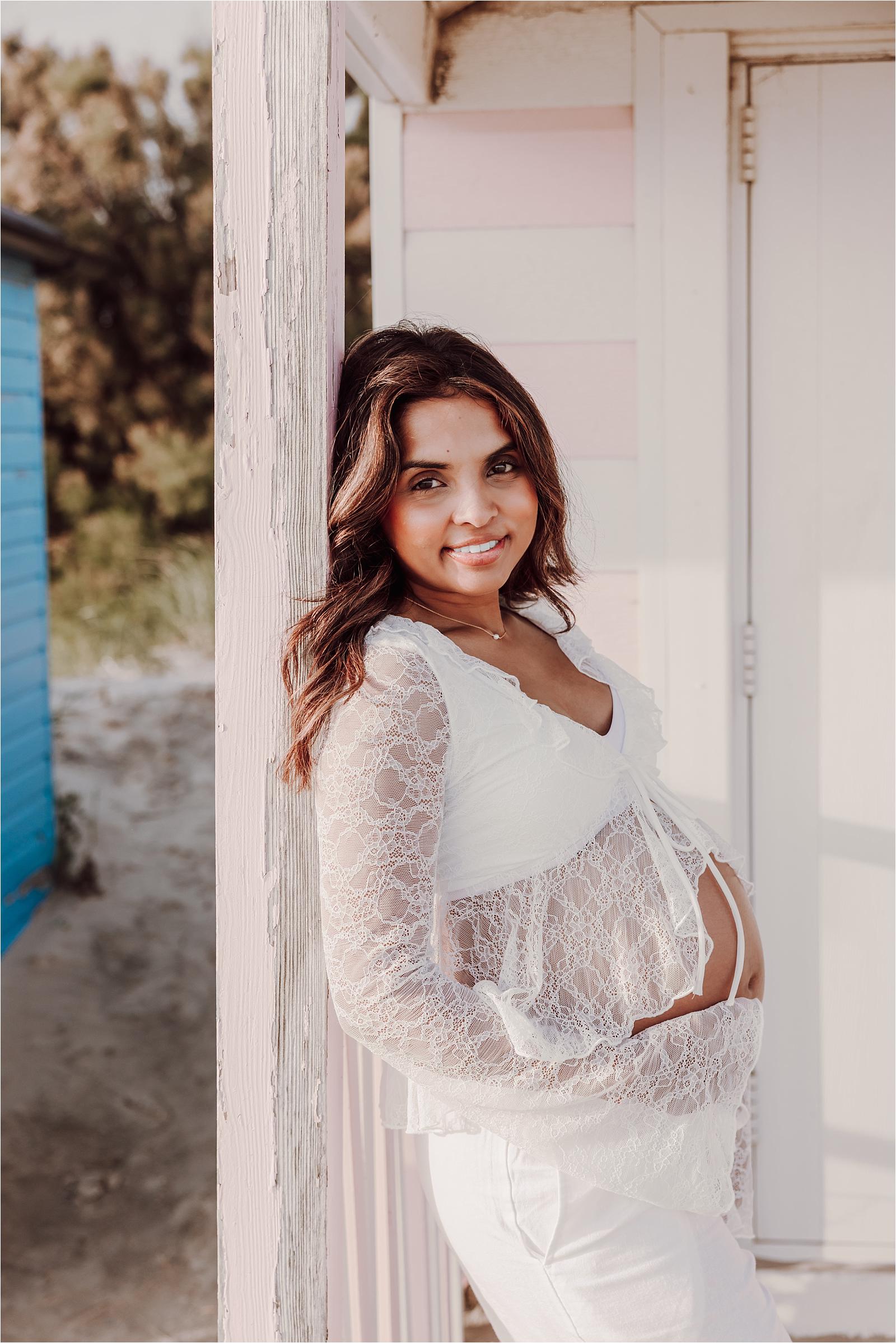 Portrait of a smiling mum-to-be in white lace during her maternity photoshoot at West Wittering
