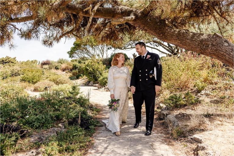 Bride and groom walking through greenery by the Rock Gardens on a summer day