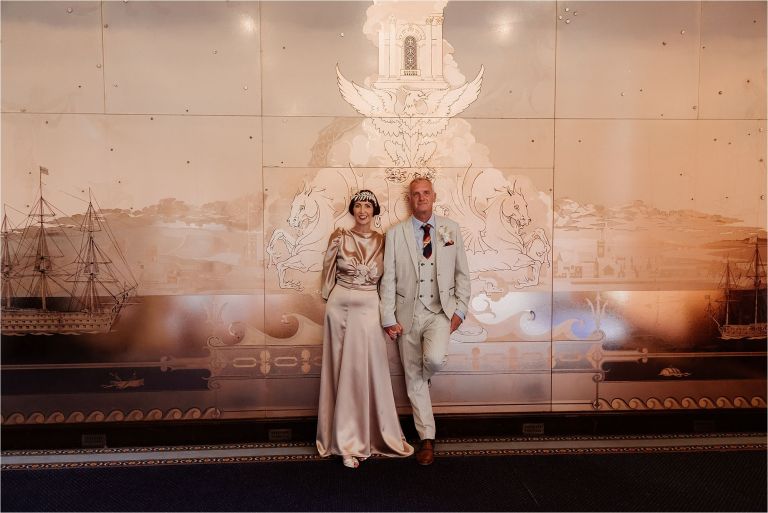 Newlyweds standing in front of an illuminated fountain in the evening
